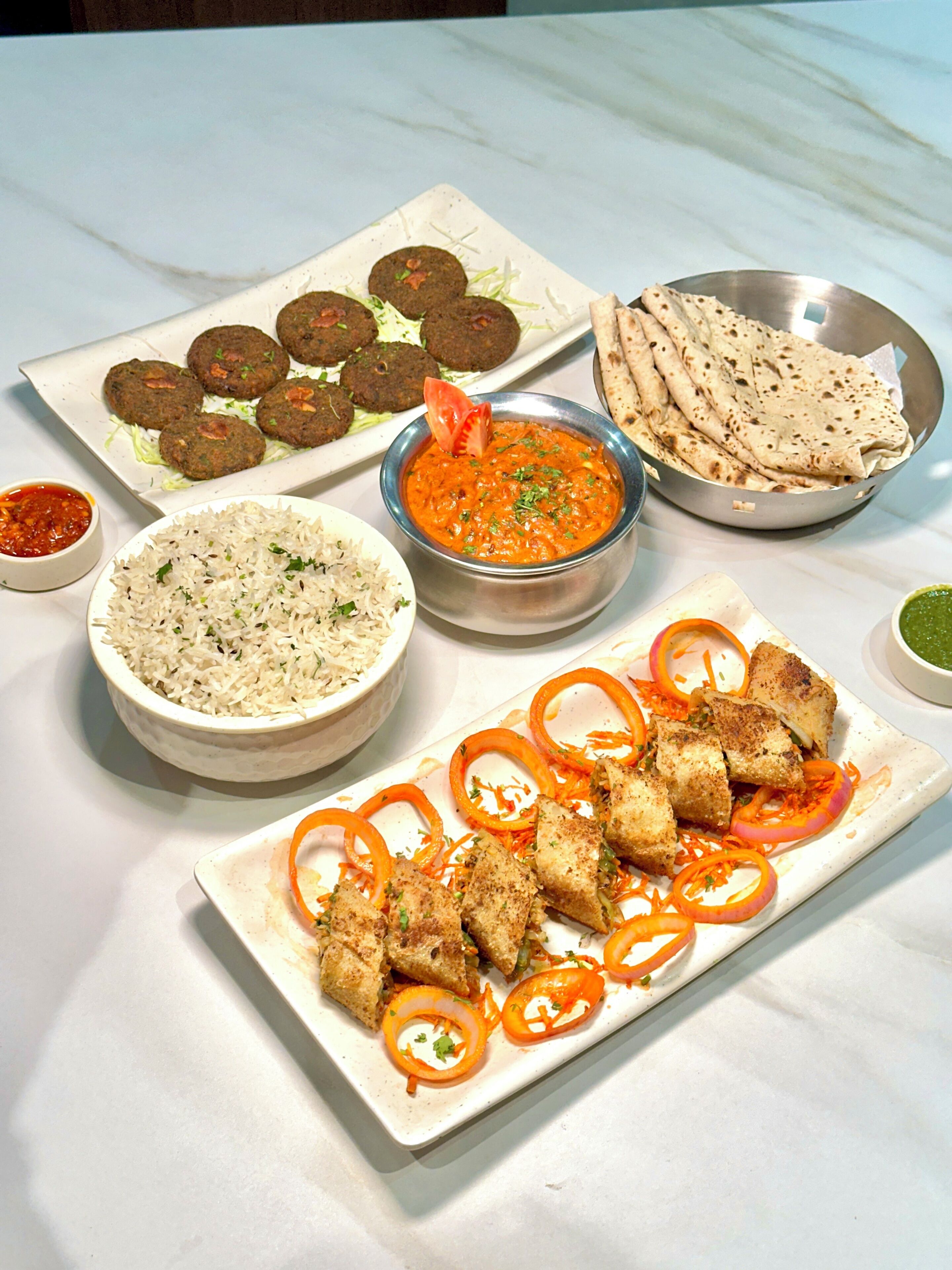 A variety of dishes including rice, flatbreads, and a bowl of sauce.
