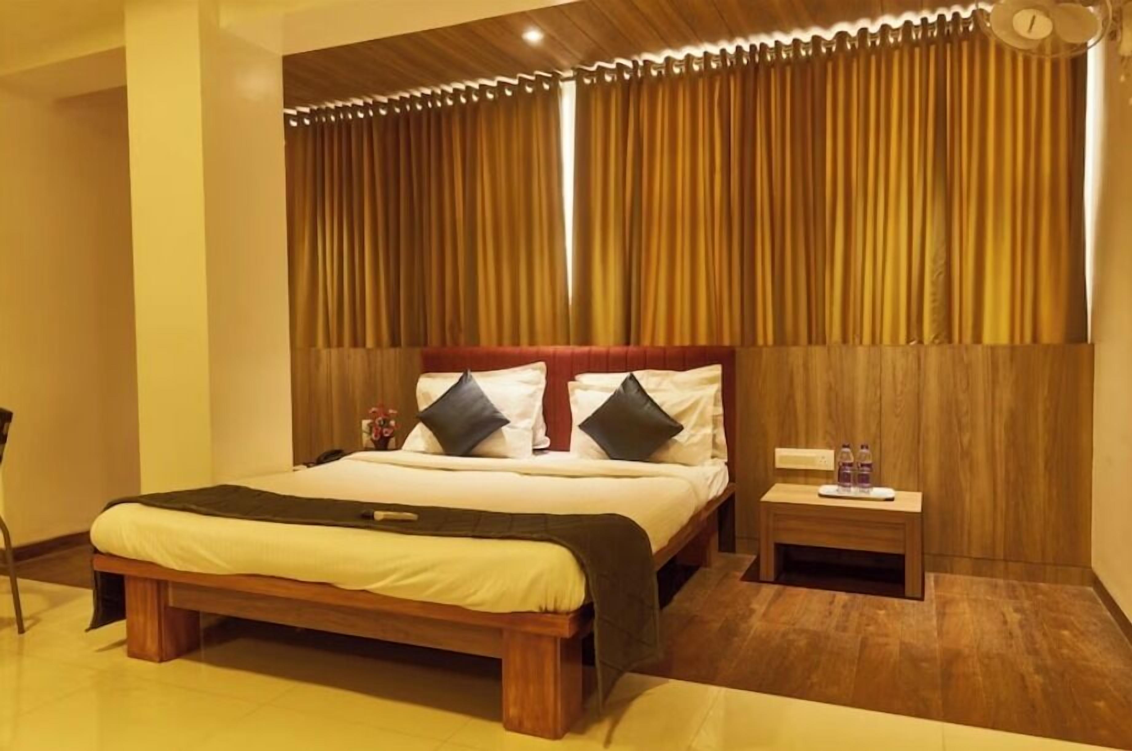 Een hotelkamer met een houten bed, een nachtkastje en een kleine tafel met flessen.