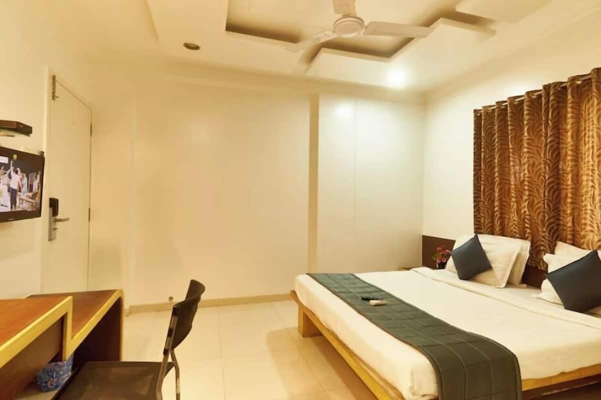 A hotel room with a bed, a desk, and a chair.