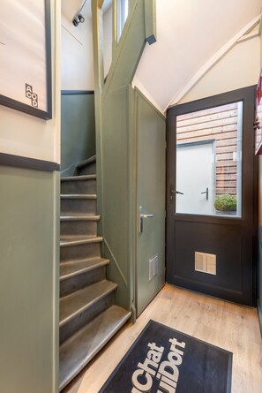 A staircase leading to a door with a window, a doormat with text, and a framed picture on the wall. - Au Chat Qui Dort Lille - Archives 18 (Lille)