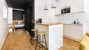Une cuisine moderne avec des meubles blancs, un plan de travail en bois et deux tabourets de bar.