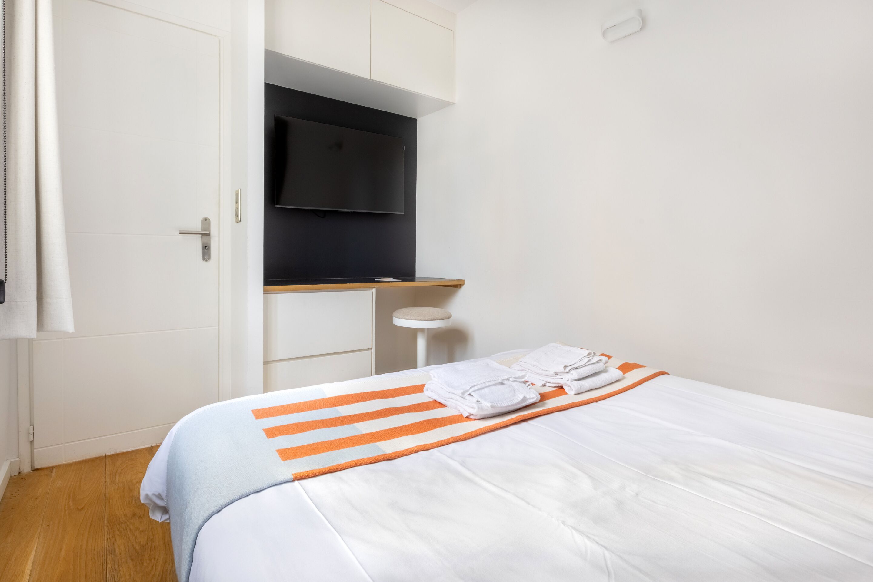 Een hotelkamer met een bed, bureau en televisie.