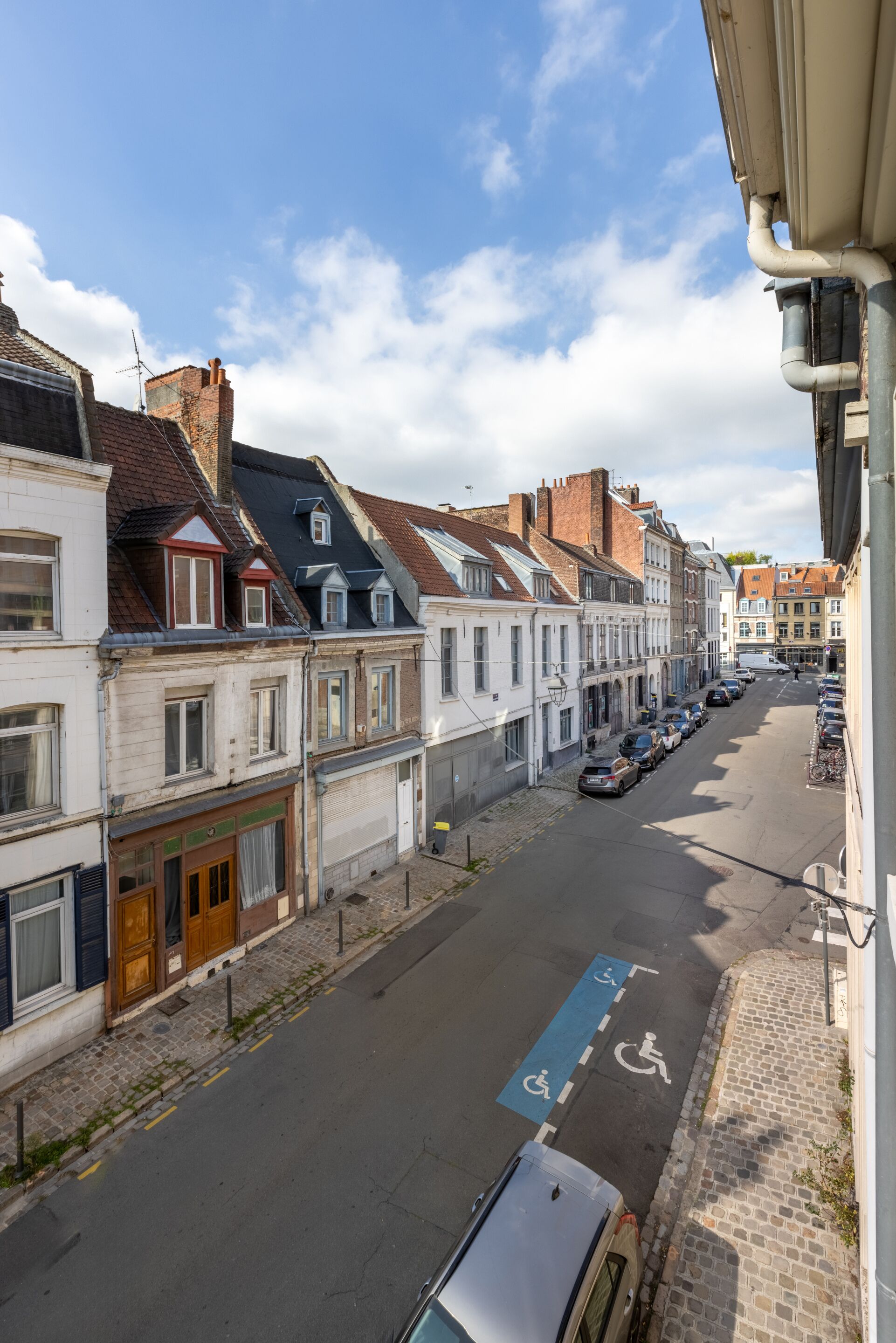 Vista de una calle con edificios históricos, un área de estacionamiento y un espacio reservado para discapacitados, identificado con el color azul.