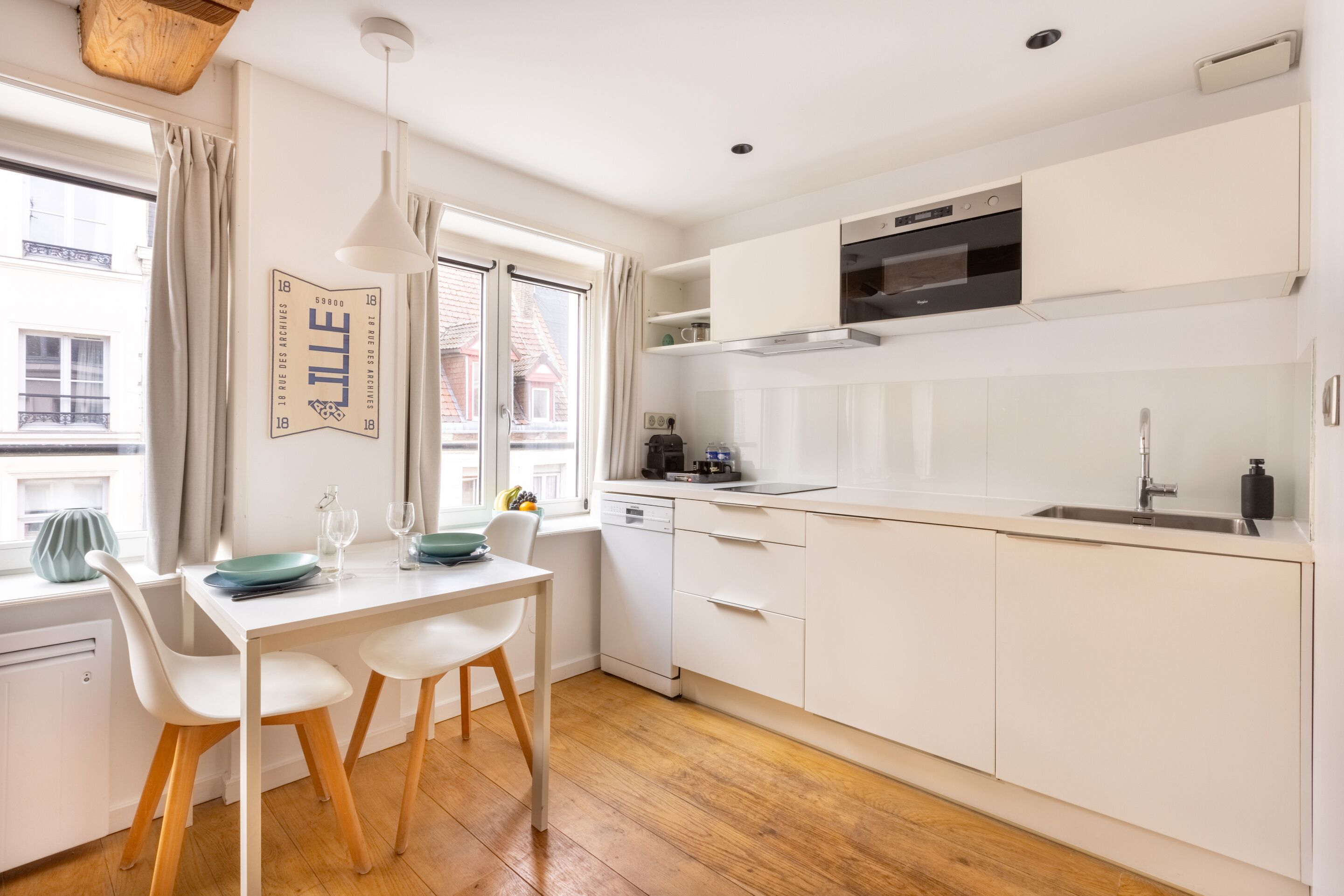 A modern kitchen with white cabinets, a built-in oven, and a window with curtains.