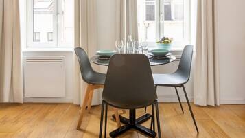 Comedor con mesa, sillas, lámpara colgante y ventana con cortinas.