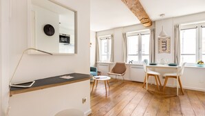 Un salon moderne avec un plancher en bois, une table ronde, un canapé et un coin repas avec des chaises.