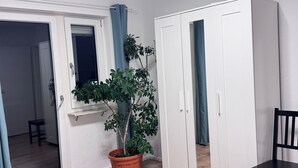 Una habitación con ventana, una planta en maceta, una silla y un armario.