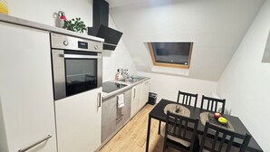 Una cocina compacta con horno integrado, pileta y comedor con mesa y sillas.
