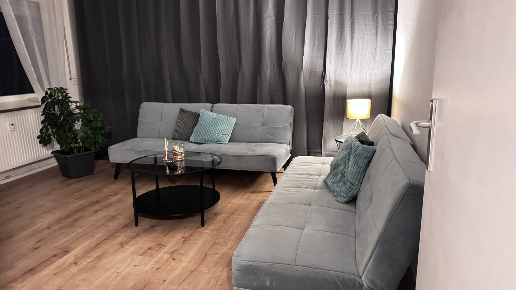 A modern living room with a grey sofa, a round coffee table, and a potted plant.