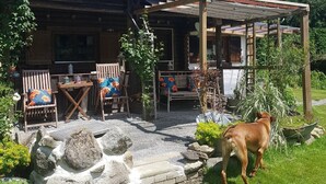 A rustic wooden cabin with a covered porch, stone steps, and outdoor seating.