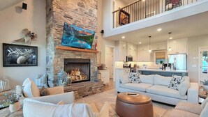 Amplia sala de estar con chimenea de piedra, televisor montado y una zona de estar acogedora.