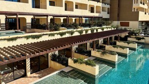 Un hotel con piscina, mobiliario exterior y balcones con plantas.