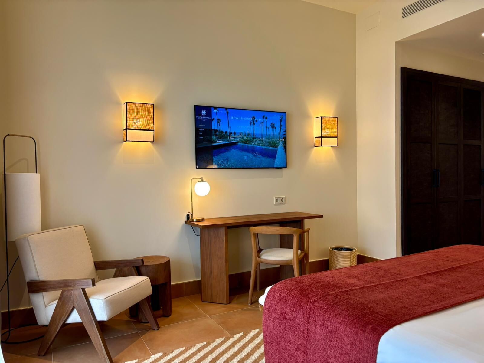 Ein Hotelzimmer mit einem Bett, einem Schreibtisch, einem Sessel, einem Fernseher und zwei Wandleuchten.