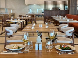 Un restaurante con varias mesas, cada una dispuesta con platos, vasos y cubiertos.
