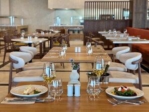 A restaurant with multiple tables, each set with plates, glasses, and cutlery. - Punta Bermeja Premium Beach Hotel (El Puerto de Santa Maria)
