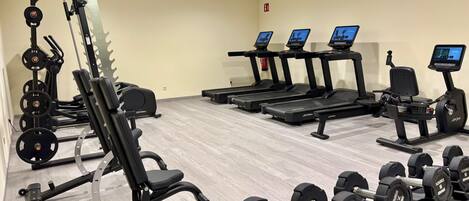 A gym with various exercise equipment including treadmills, weight machines, and dumbbells.
