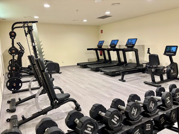 A gym with various exercise equipment including treadmills, weight machines, and dumbbells. - Punta Bermeja Premium Beach Hotel (El Puerto de Santa Maria)