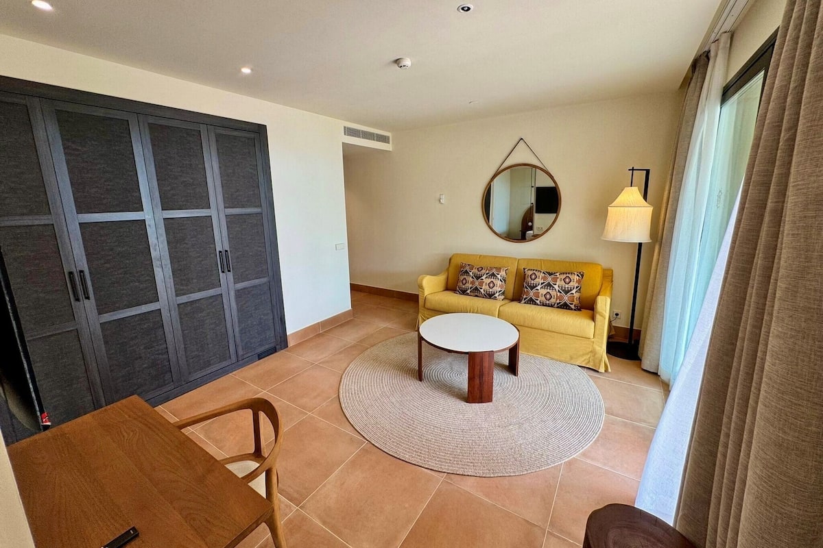 A living room with a sofa, a coffee table, a round rug, and a dining table.