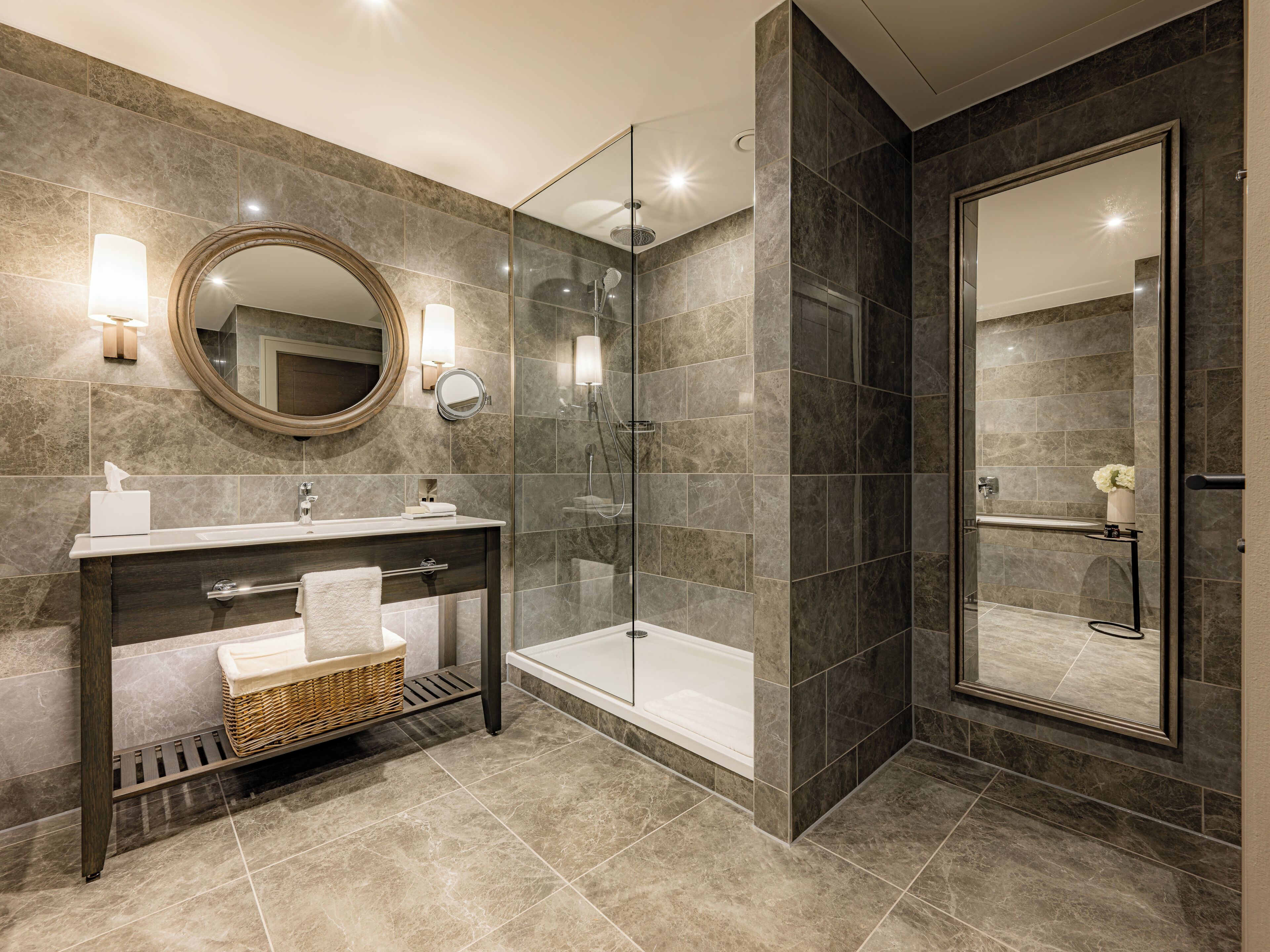 A modern bathroom with a glass-enclosed shower, a vanity with a mirror, and a bathtub.