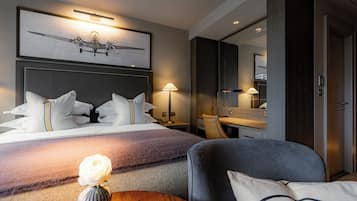 Quarto de hotel com cama, mesa de cabeceira, abajur e um espelho grande.