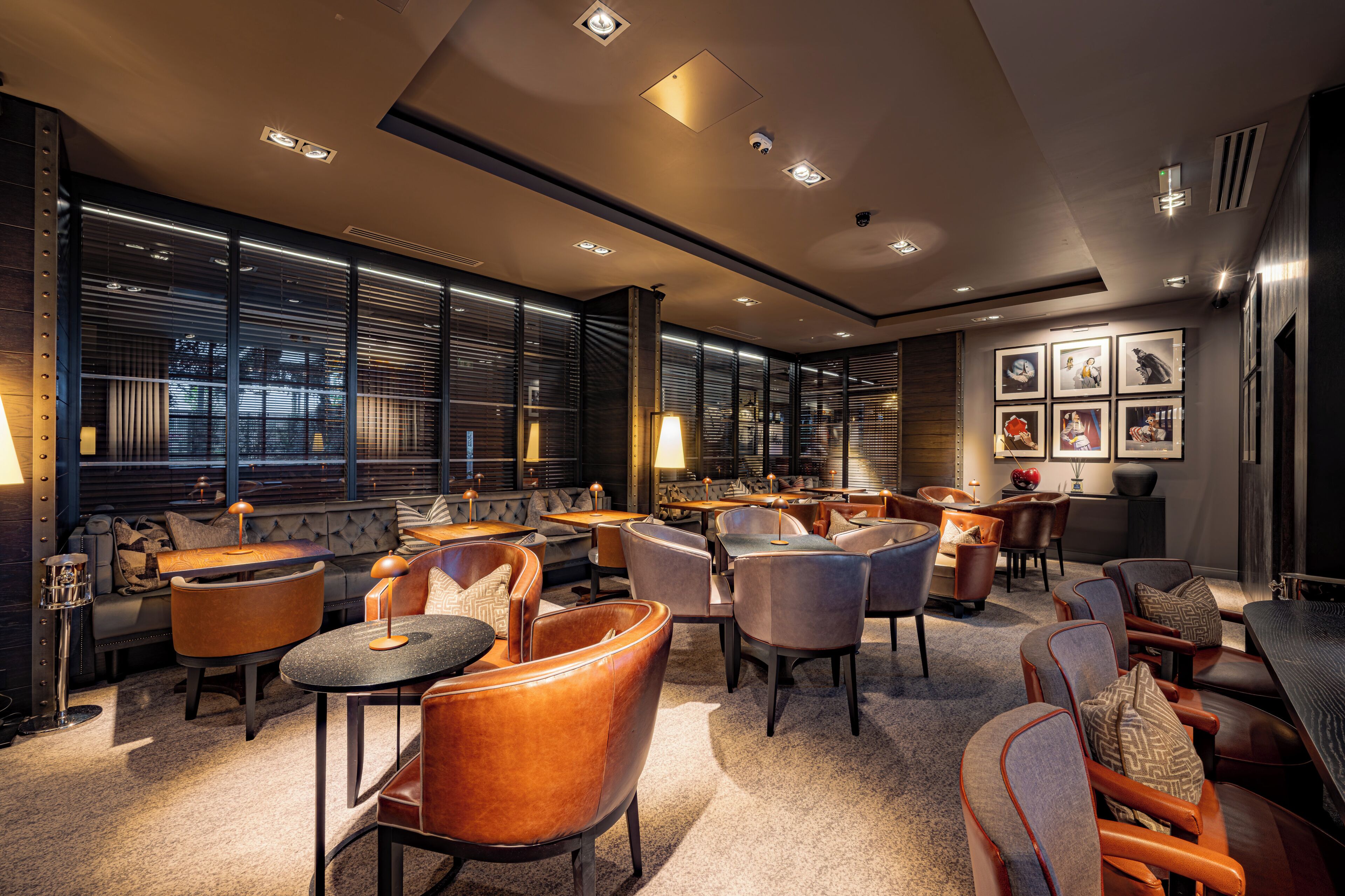 A modern interior with a mix of seating arrangements, including sofas and chairs, and a wall adorned with framed pictures.