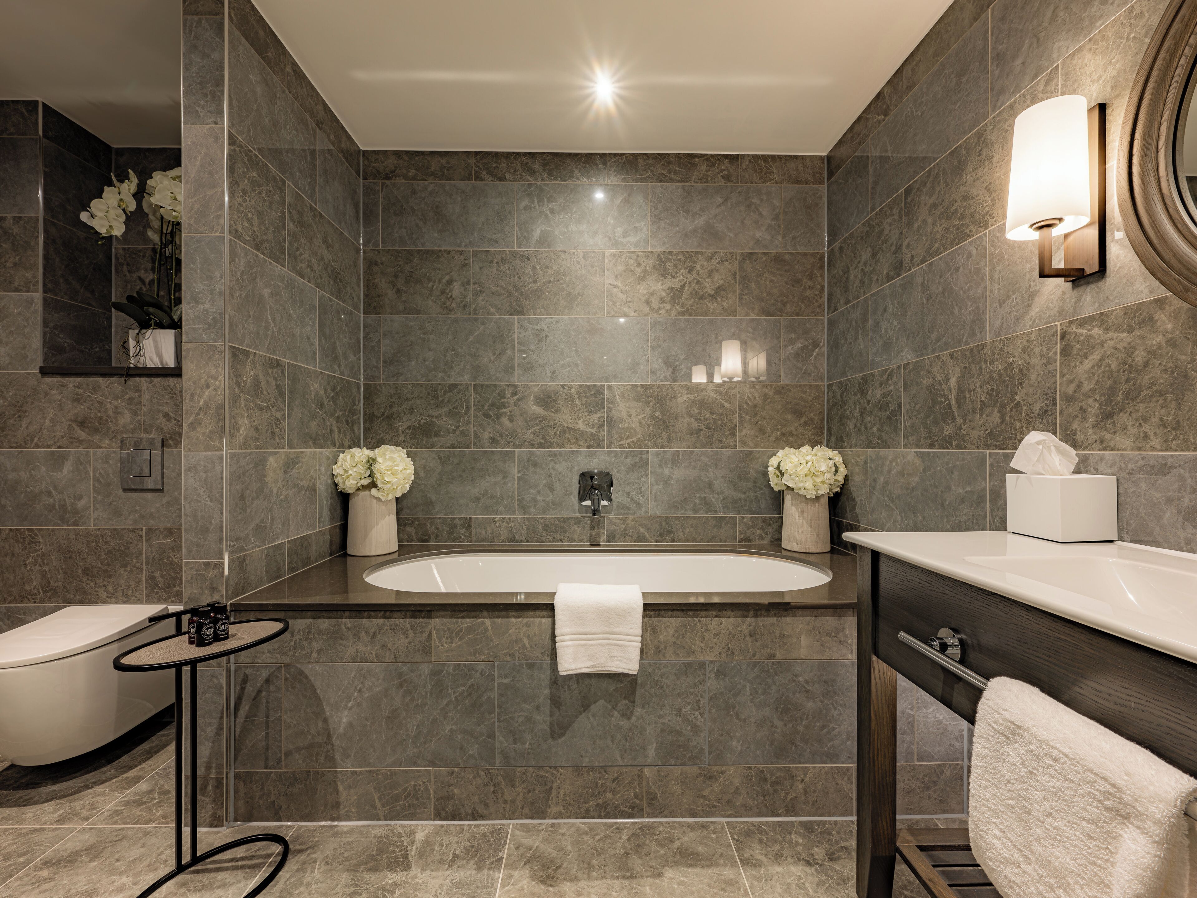 A modern bathroom with a freestanding bathtub, a toilet, and a vanity with a mirror.