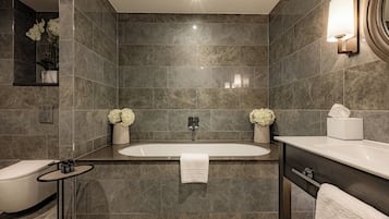 A modern bathroom with a freestanding bathtub, a toilet, and a vanity with a mirror.