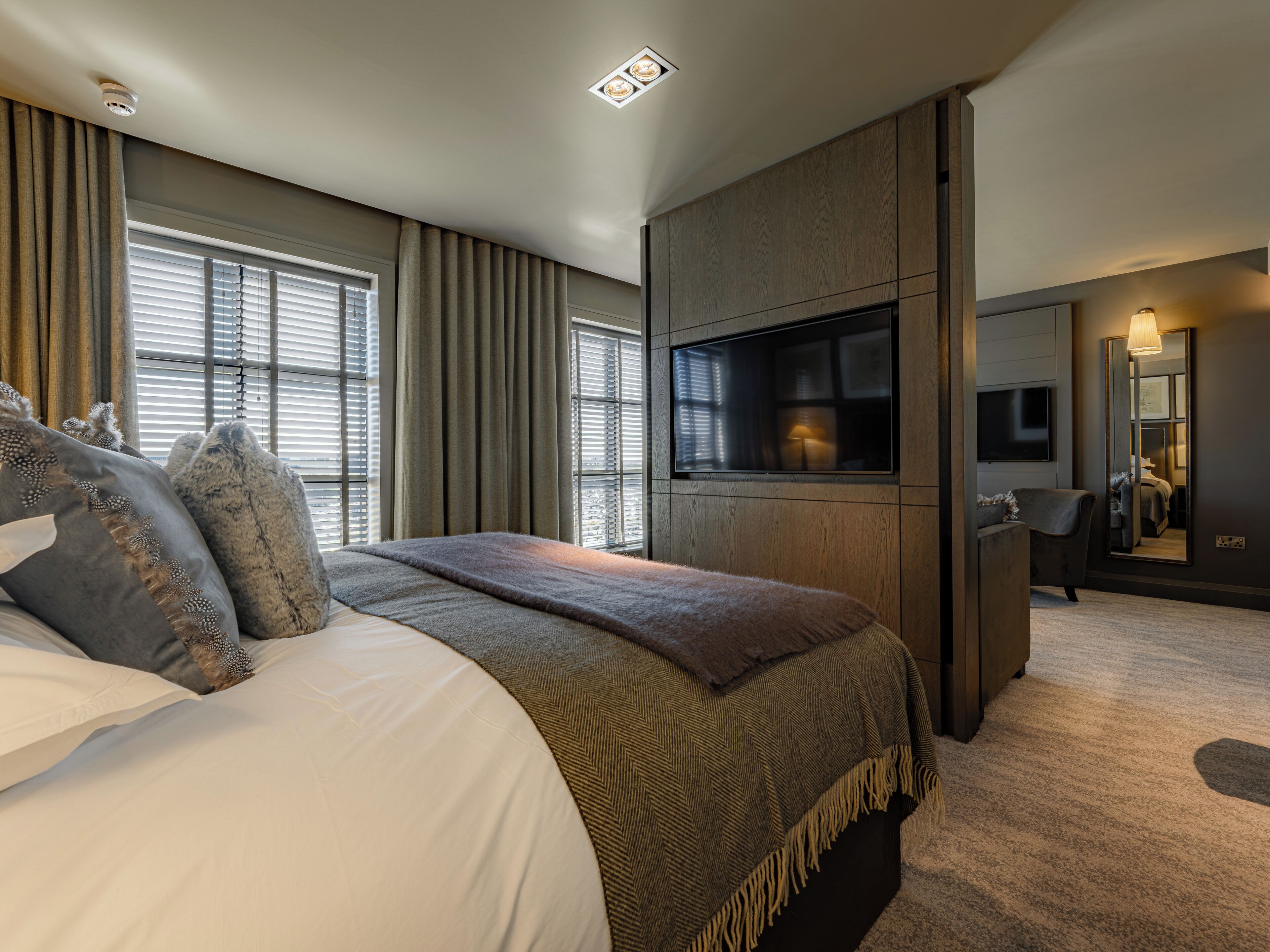 Une chambre à coucher moderne avec un grand lit, une télévision et un miroir.