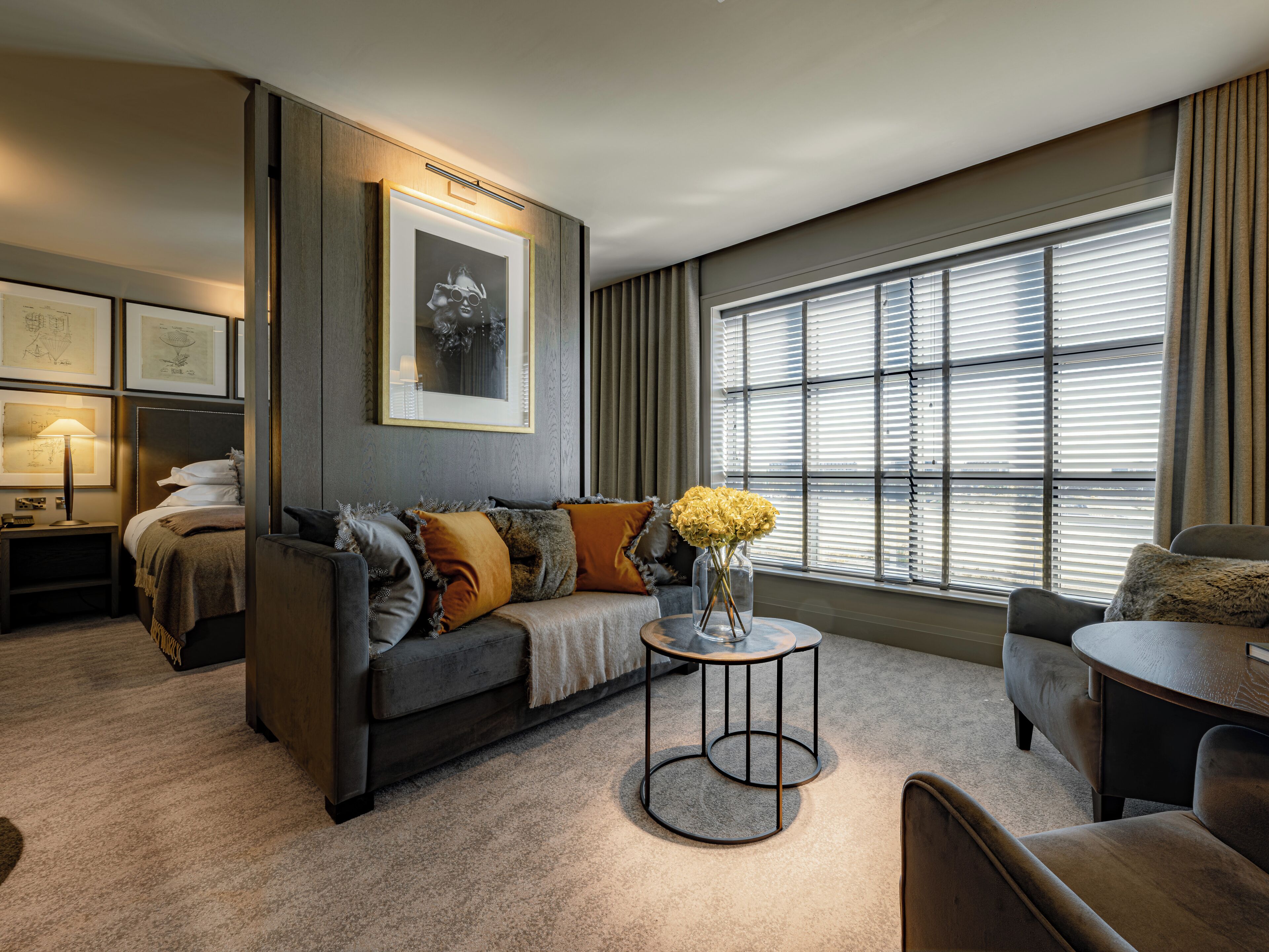 A modern living room with a sofa, a coffee table, and a large window with blinds.