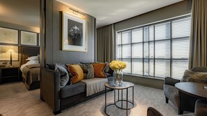 A modern living room with a sofa, a coffee table, and a large window with blinds. - Dakota Manchester Airport (Manchester)