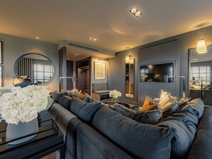 A modern living room with a grey sofa, a round mirror, and a vase of white flowers. - Dakota Manchester Airport (Manchester)