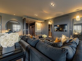 Una sala de estar moderna con un sofá gris, un espejo redondo y un jarrón con flores blancas.