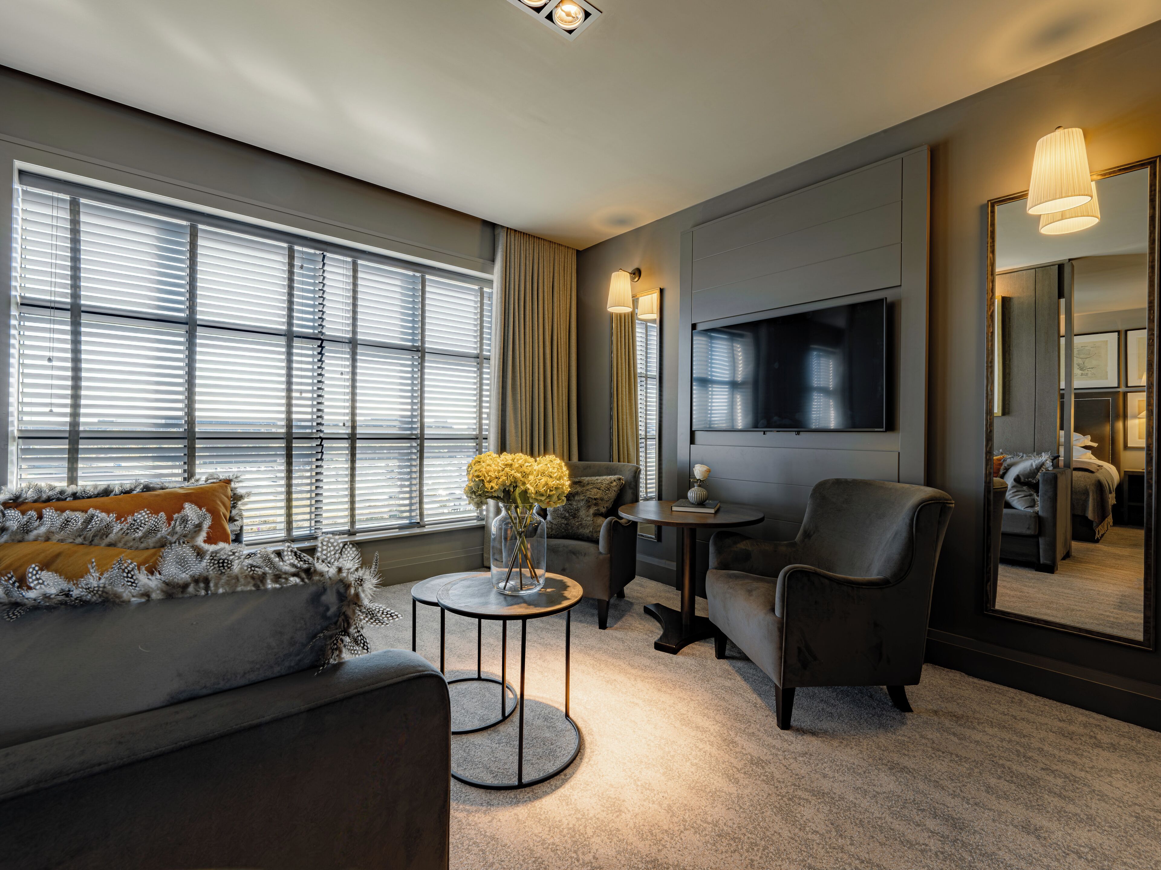 A modern living room with a sofa, armchairs, a coffee table, and a TV mounted on the wall.