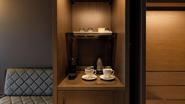 A compact kitchenette with a coffee maker, two cups, and a small shelf with jars. - Dakota Manchester Airport (Manchester)