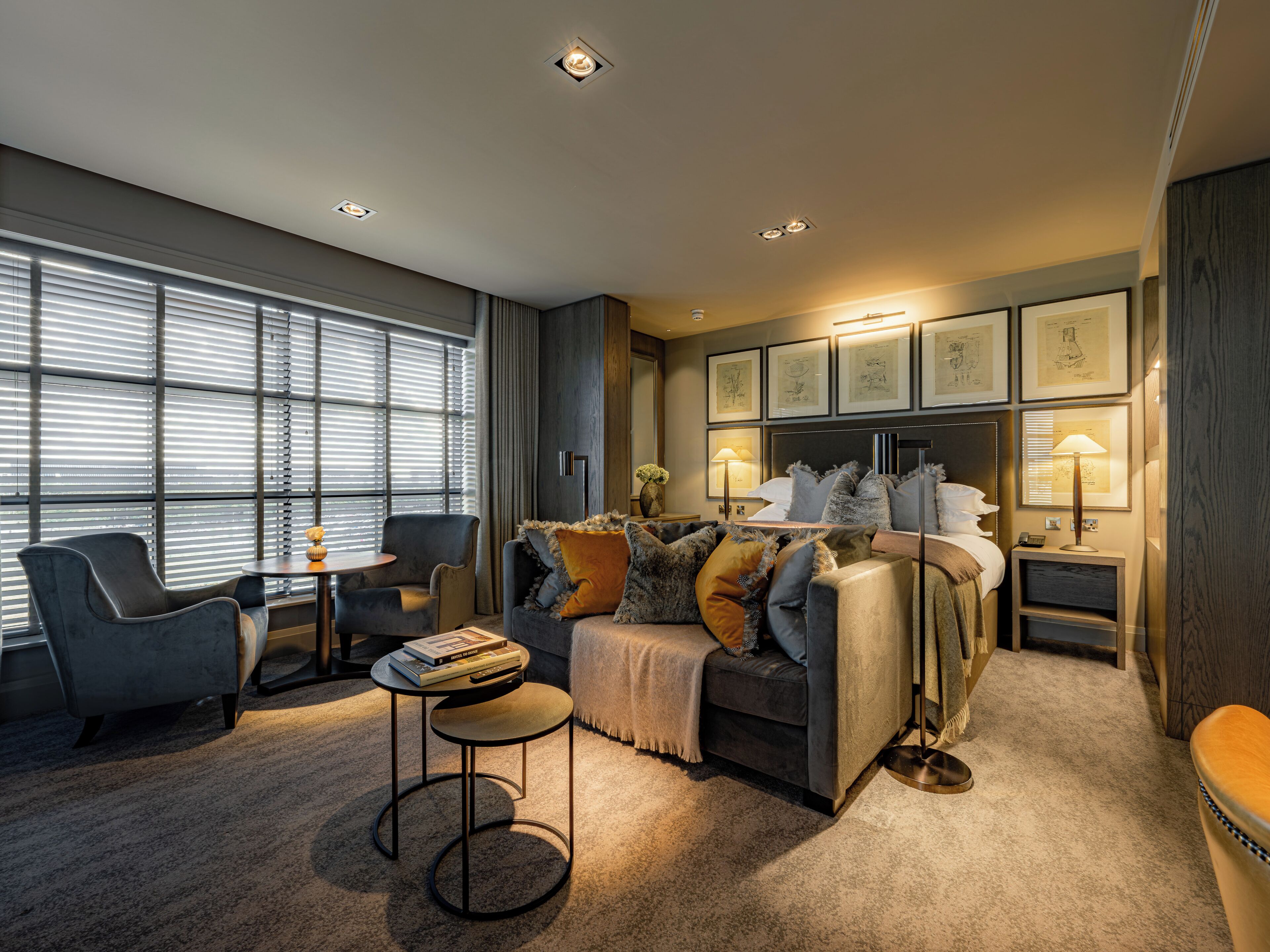 Ein modernes Hotelzimmer mit Bett, Sitzgelegenheit und Bildern an der Wand.