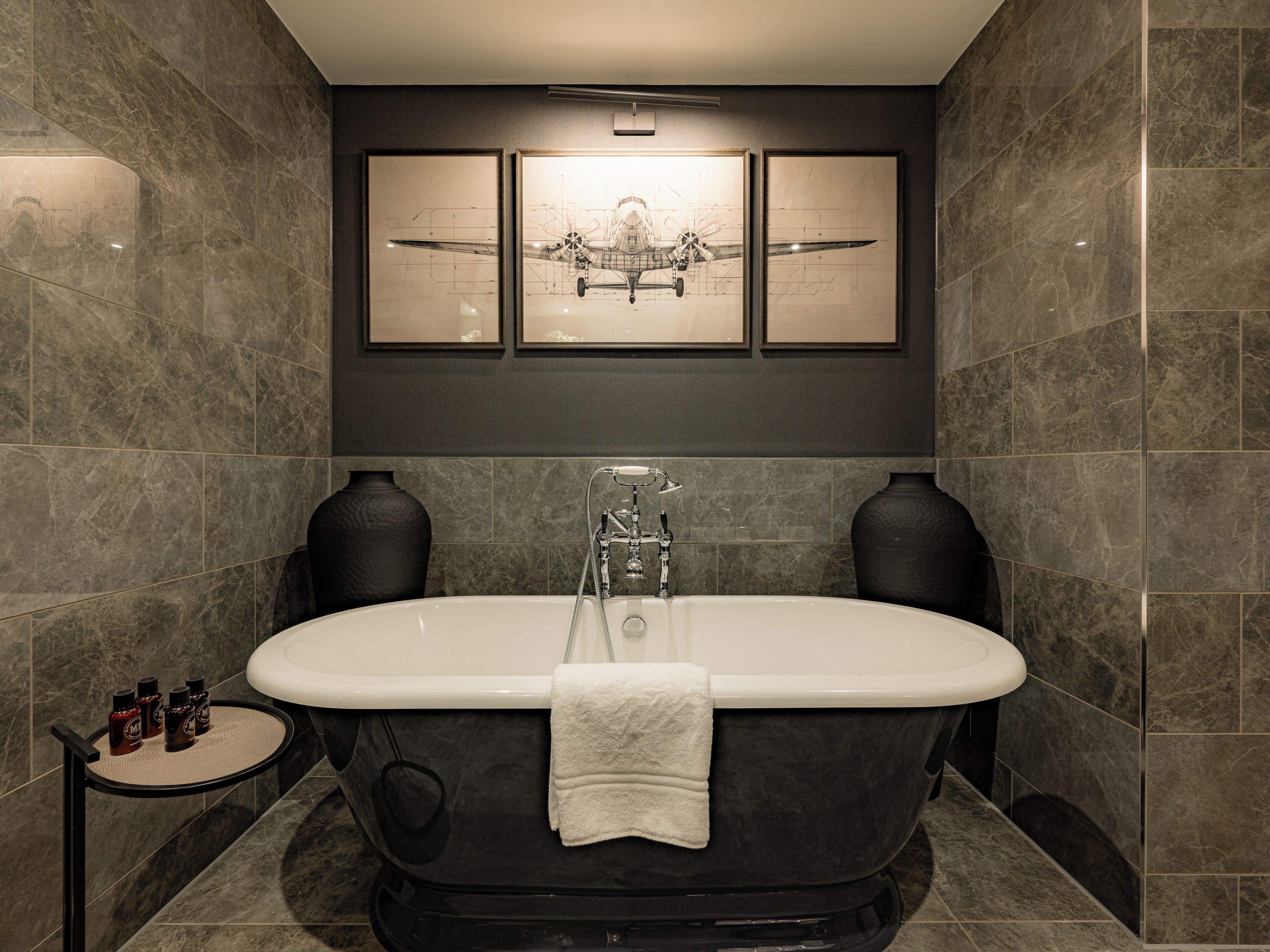 Un baño moderno con una bañera independiente, paredes de mármol y una obra de arte enmarcada.