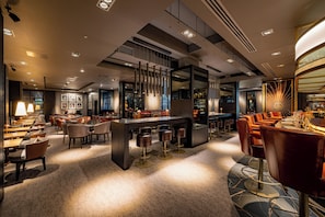 Una hall d'hotel moderna con zona bar, posti a sedere e un'isola centrale.