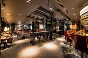 A modern hotel lobby with a bar area, seating arrangements, and a central island.