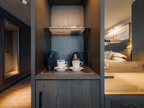 A compact hotel room with a kitchenette, a bed with white linens, and a view of the cityscape. - Dakota Manchester Airport (Manchester)
