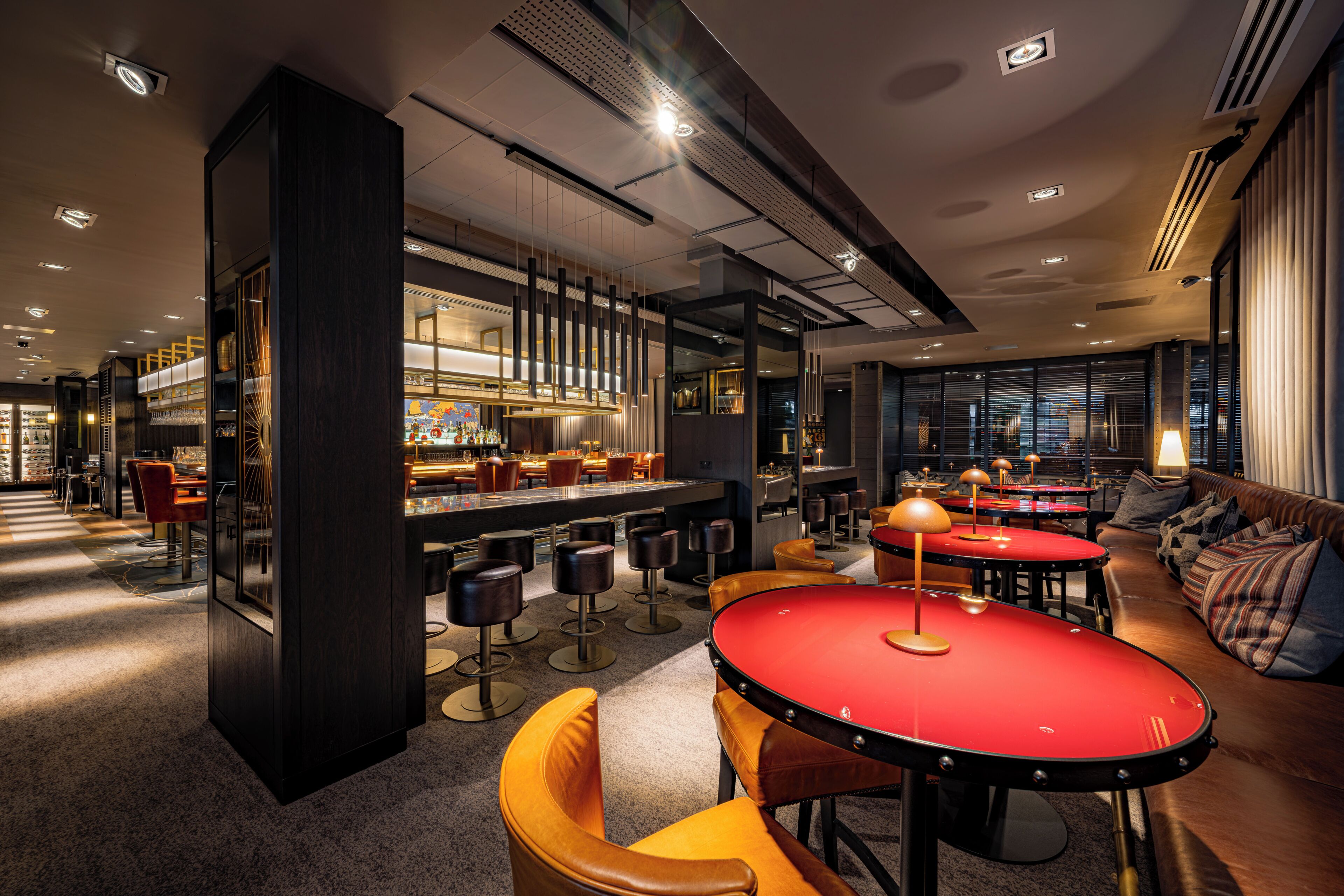 A modern bar area with high stools, a red table, and a bar counter.
