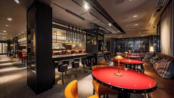 A modern bar area with high stools, a red table, and a bar counter.