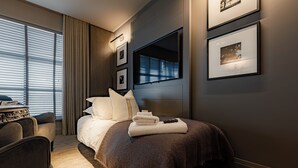 A modern hotel room with a large bed, a desk, and a view of the city through the window. - Dakota Manchester Airport (Manchester)