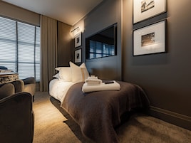 Habitación de hotel moderna con una cama grande, un escritorio y vistas a la ciudad por la ventana.