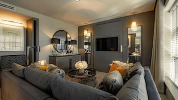 A modern living room with a grey sofa, a coffee table, and a flat-screen TV mounted on the wall.
