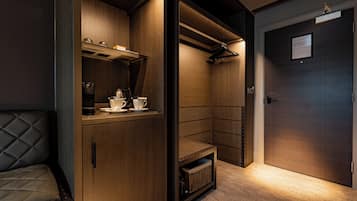 A compact, modern room with built-in cabinetry, a seating area, and a door with a sign.