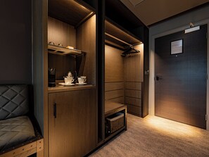 A compact, modern room with built-in cabinetry, a seating area, and a door with a sign. - Dakota Manchester Airport (Manchester)