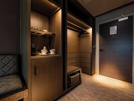 Una habitación compacta y moderna con muebles empotrados, un rincón de descanso y una puerta con un letrero.