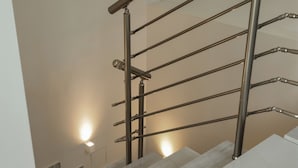 Una moderna scala con ringhiere in metallo e un lampadario a parete.