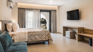 Una camera d'albergo moderna con un letto grande, un divano, una TV a parete e un balcone con tende.