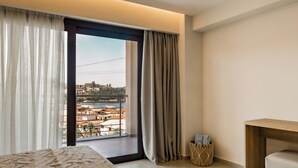 Una camera d'albergo moderna con una grande finestra, un letto, un tavolino e vista sulla città.
